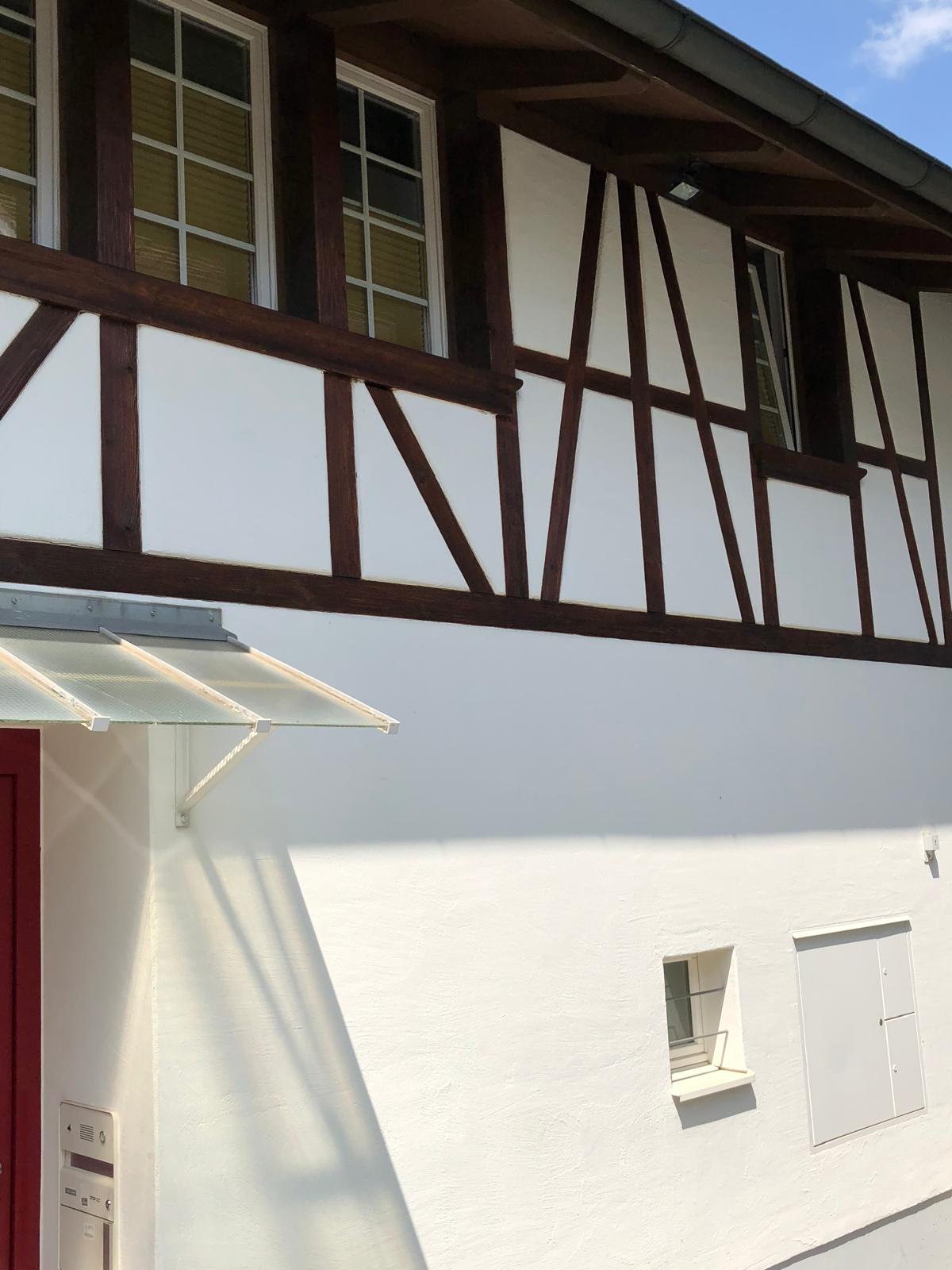 Frisch gestrichene Riegelhaus-Fassade mit Vordach