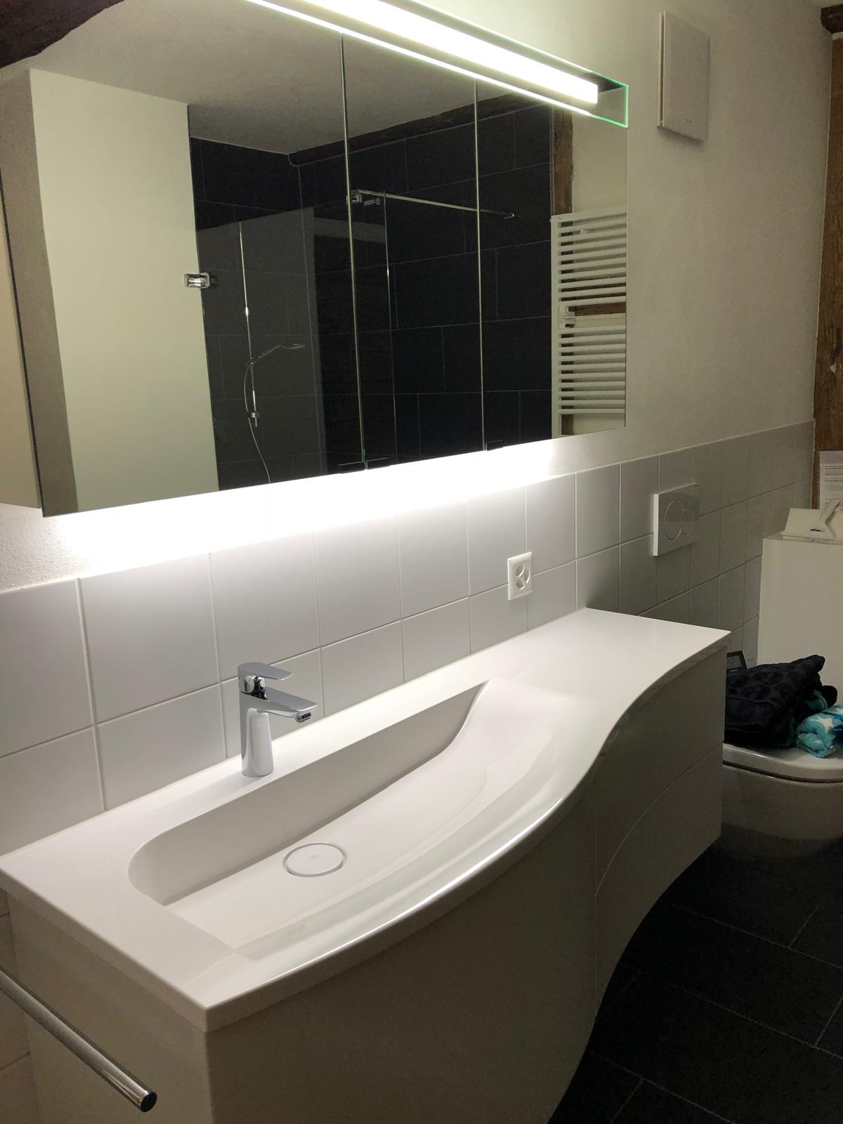 Modernes Badezimmer mit Waschtisch und beleuchtetem Spiegelschrank